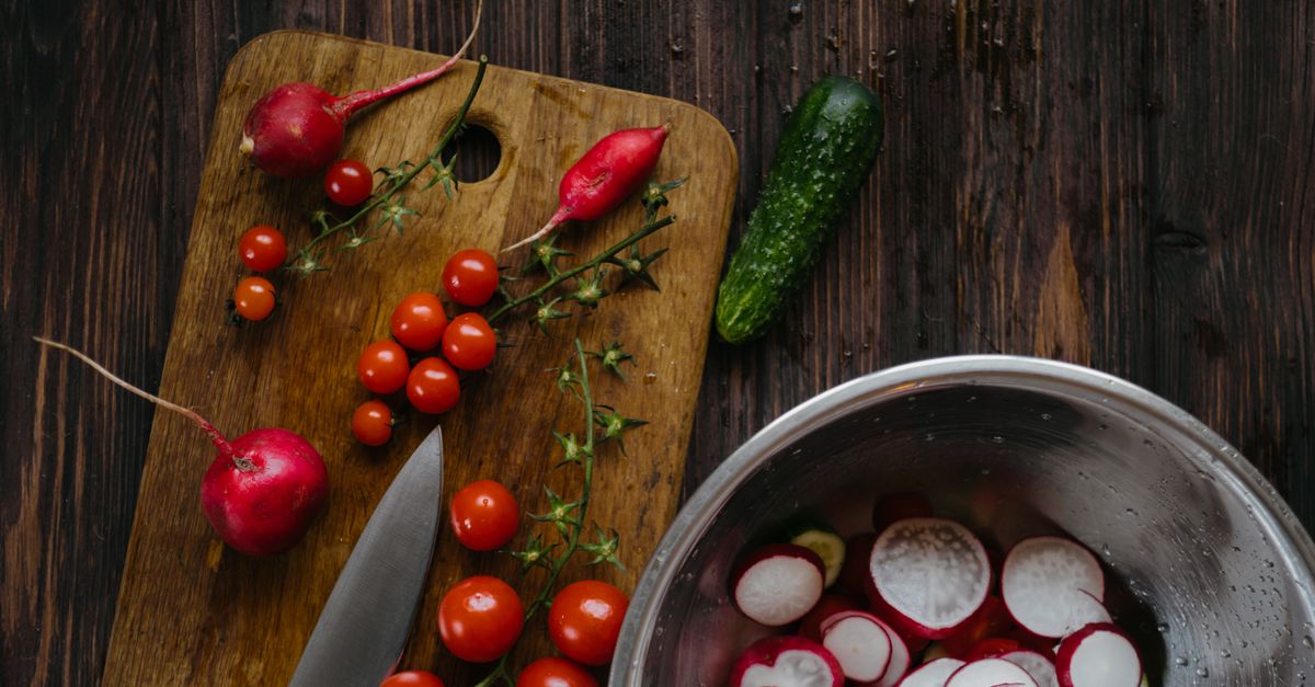 Fresh vegetables and a knife on a wooden board, the food side of a men's calorie deficit.