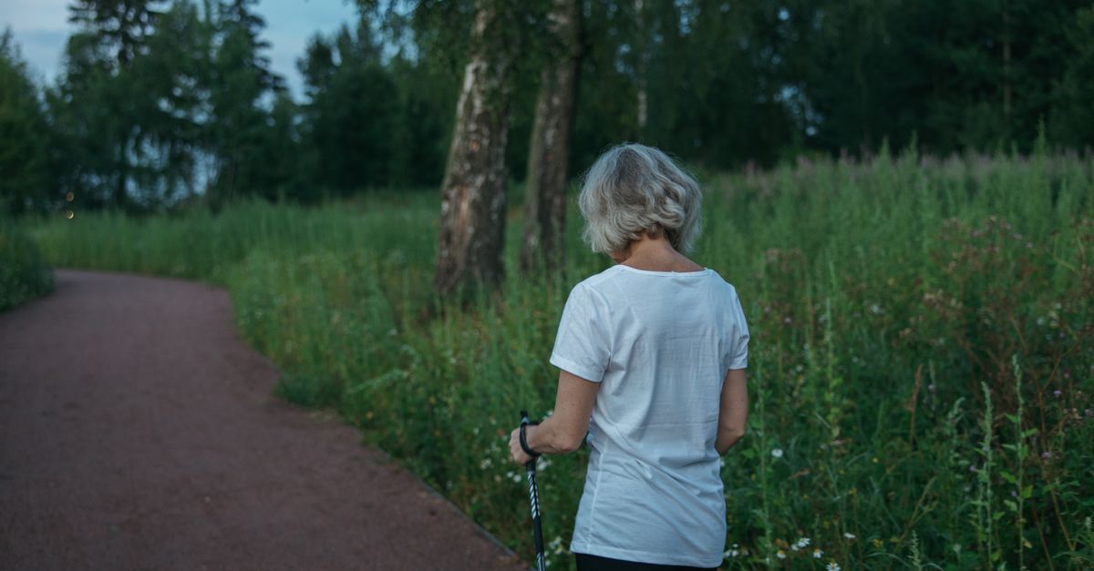 Woman walking with poles along a grassy park path