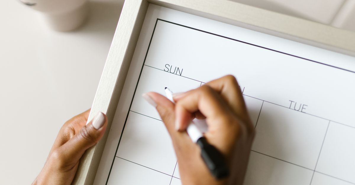 A hand marking dates on a wall calendar, planning what follows the four weeks of the Switch-On diet