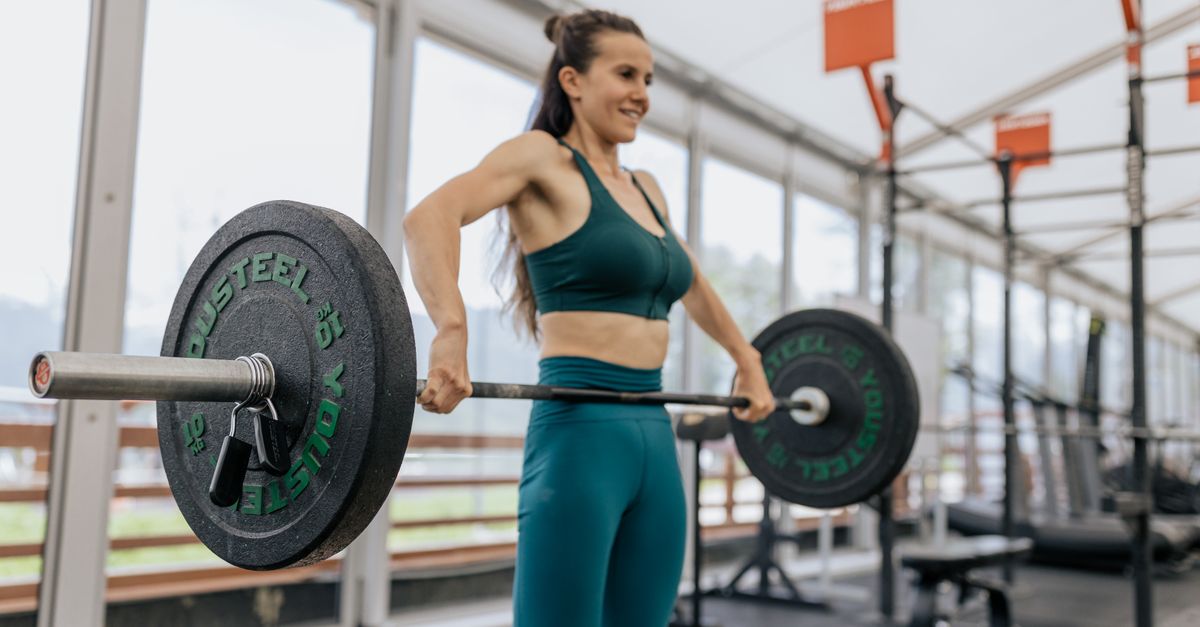 Woman lifting a loaded barbell in a gym, the short maximal effort creatine fuels