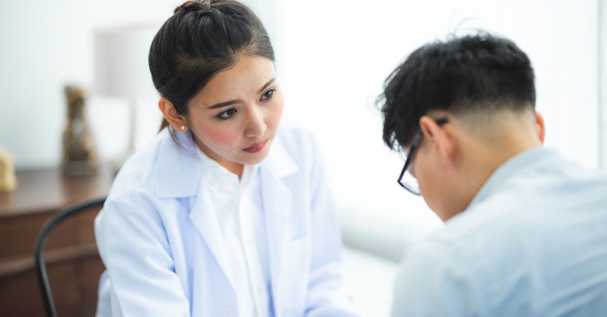 A doctor in a white coat listening as a patient describes changed hunger and weight